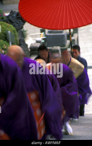 Dynamisches Bild lila Robe Mönche aufsteigende Treppe unter roten Regenschirm buddhistischen Shinto-Tempel am Narita Japan Stockfoto