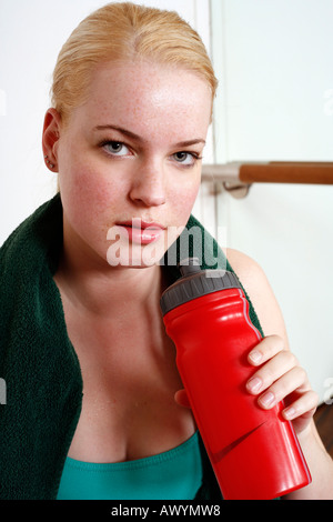 Junge Frau in Übung Ausrüstung mit einer Flasche Wasser Stockfoto