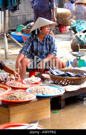 Asien Fernost Vietnam, Hoi an Markt, hübsche junge Dame in nicht bai tho Nationalkleid Verkauf einer Auswahl an frischem Fisch aus Pflaster Stall Stockfoto