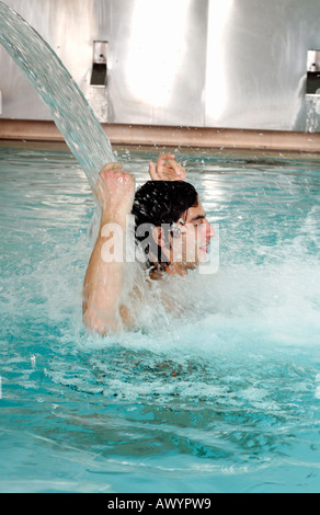 Junge Mann stand unter Wasserspray im Whirlpool Stockfoto
