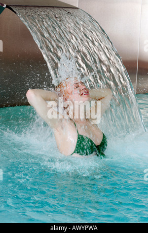 Junge Frau, die unter Wasserspray im Whirlpool Stockfoto