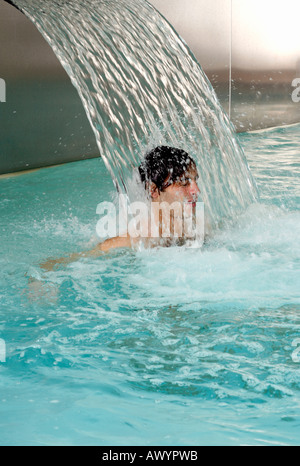 Junge Mann stand unter Wasserspray im Whirlpool Stockfoto