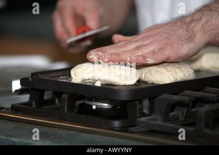 männliche Koch tätschelte auf traditionelle irische Soda Brot Kochen auf eine flache Grillpfanne auf dem Kochfeld Gasherd Stockfoto