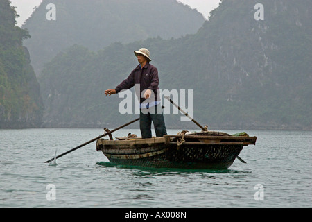 Ein Fischer bei der Arbeit an Bord eines kleinen Bootes in den Gewässern der HALONG Bucht VIETNAM Stockfoto