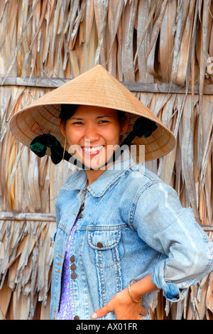 Asien Fernost Vietnam , Mekong Delta , ziemlich junge native Mädchen in nicht bai tho , konischen Hut , stoppt Arbeit an Passanten durch Lächeln Stockfoto