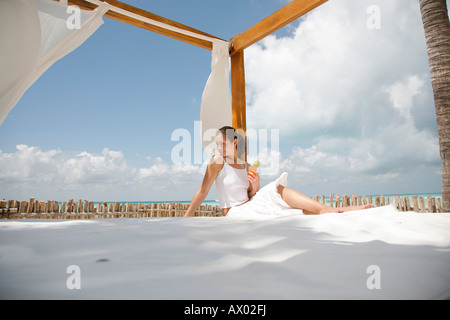 Junge Frau sitzt an einem Strand mit Cocktail, Isla Mujeres, Cancun, Mexiko. HERR-03-05-2008 Stockfoto