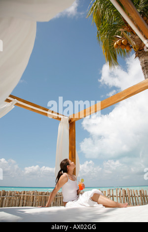 Junge Frau sitzt an einem Strand mit Cocktail, Isla Mujeres, Cancun, Mexiko. HERR-03-05-2008 Stockfoto