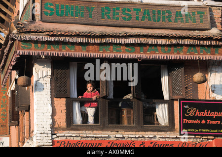 Nepal, Bhaktapur, Mädchen mit Blick vom Restauants geschnitzten Holzfenster Stockfoto