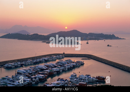 China, Hong Kong, Sonnenaufgang über Peng Chau Island mit Discovery Bay Marina im Vordergrund Stockfoto