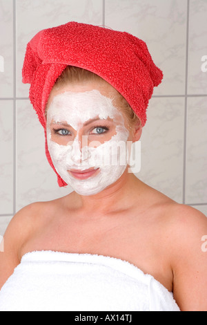Junge blonde Frau eingehüllt in weißen Handtuch im Bad stehen, tragen eine Gesichtsmaske, Vulkaneifel, Deutschland, Europa Stockfoto
