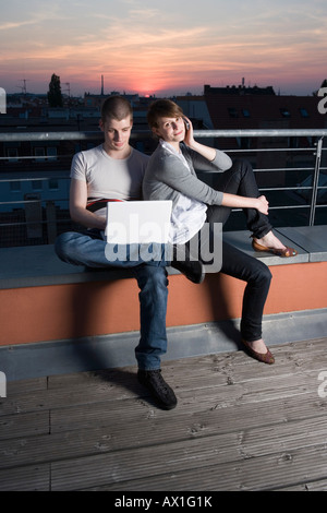 Ein junges Paar mit einem Laptopcomputer auf der Dachterrasse Stockfoto
