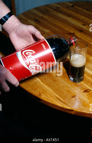 Coca Cola Flasche in ein Glas gegossen wird Stockfoto