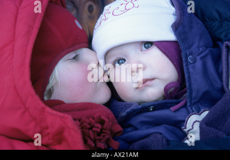 Mädchen, die ihren kleinen Bruder auf die Wange küssen Stockfoto