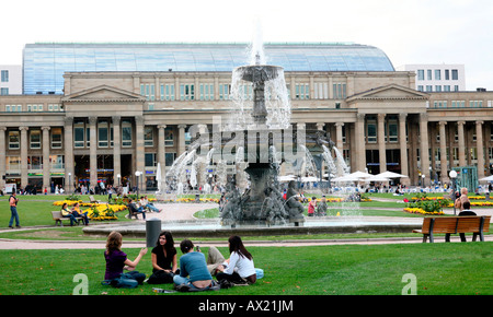 Jugendliche sitzen zusammen auf dem Rasen vor dem Brunnen am Schlossplatz, Stuttgart, Baden-Württemberg, Deutschland, Euro Stockfoto