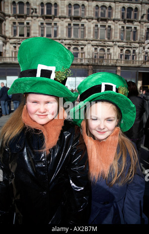 zwei junge Mädchen im grünen Hüten und orangefarbene Bärte stehend warten auf die Parade und Karneval am St. Patricks Tag Belfast Stockfoto