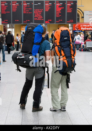zwei Backpacker bei Zug-Bahnhof-Informationstafel Stockfoto