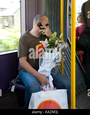 Fahrgast in der Straßenbahn sitzen mit Blumenstrauß über sein Handy Stockfoto