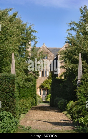 EIN PFAD, FLANKIERT VON ZWEI HÖLZERNEN SÄULEN IM GARTEN AM GUTSHOF SOMERSET VOM GARTEN DESIGNER SIMON JOHNSON UK Stockfoto