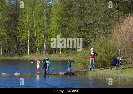 Mutter und Kinder auf einem kleinen Gartenteich, Finnland Stockfoto