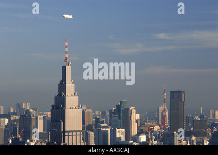 Ein Zeppelin Luftschiff Zugehörigkeit zu Nippon Luftschiffe fliegen über die Wolkenkratzer der Innenstadt von Tokio, einschließlich Tokyo Tower, Japan Stockfoto