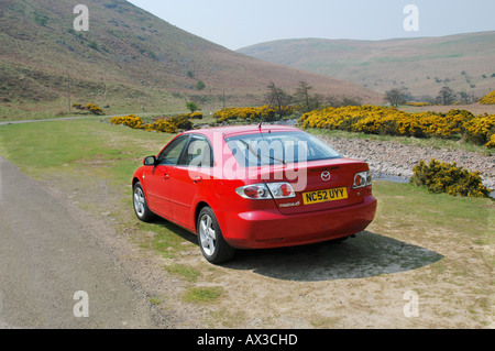 Rückansicht eines roten Mazda 6 Limousine Auto geparkt an der Seite der Straße in der Landschaft in Großbritannien. Stockfoto