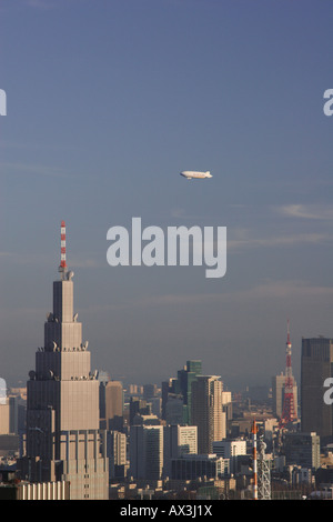 Ein Zeppelin Luftschiff Zugehörigkeit zu Nippon Luftschiffe fliegen über die Wolkenkratzer der Innenstadt von Tokio, einschließlich Tokyo Tower, Japan Stockfoto