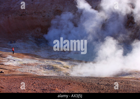 Ein Mann steht am Rande des einen dampfenden und Rauchen Vulkankrater im Altiplano von Bolivien. Stockfoto