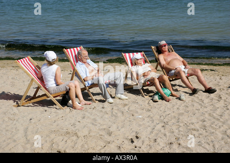 Rentner, Sonnenbaden am Strand auf den Liegestühlen an Llandudno Stockfoto