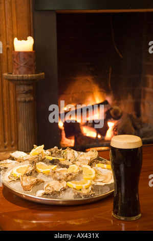 Nordirland, Fermanagh, Enniskillen. Guinness und Austern im Vordergrund des Feuers im Lough Erne Golf Resort. Stockfoto