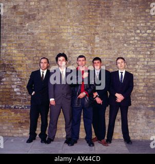 Die üblichen Verdächtigen. Eine Bande Männer in Anzügen gegen eine Ziegelmauer. Vintage 1990er Jahre Stockfoto