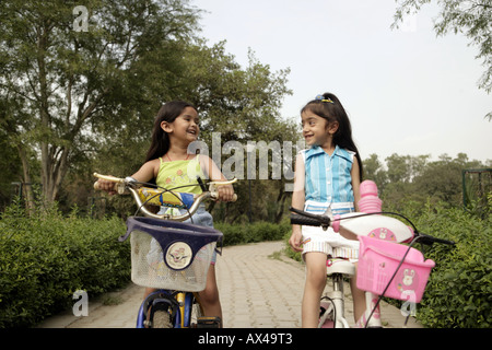 Zwei Mädchen Fahrrad in einem Park und lächelnd Stockfoto