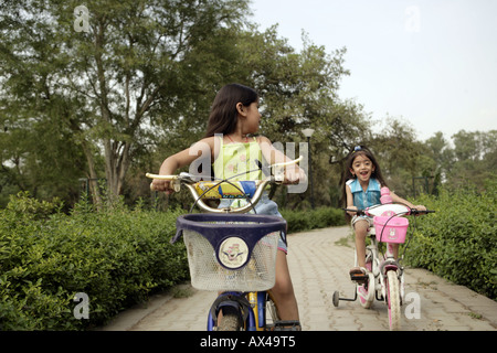 Zwei Mädchen Fahrrad in einem Park und lächelnd Stockfoto
