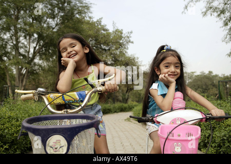Porträt von zwei Mädchen Fahrrad in einem Park und lächelnd Stockfoto