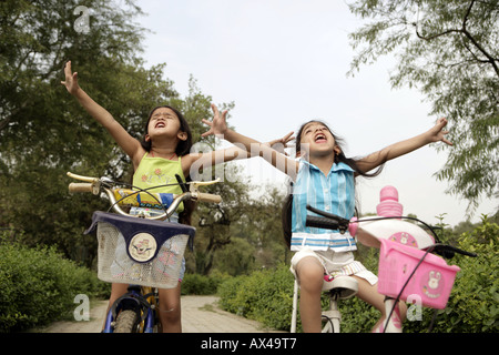 Niedrigen Winkel Ansicht von zwei Mädchen Fahrrad in einem Park und lachen Stockfoto