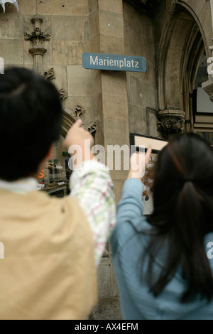 Zwei asiatische Menschen zeigt auf ein Schild mit der Aufschrift "Marienplatz" Stockfoto