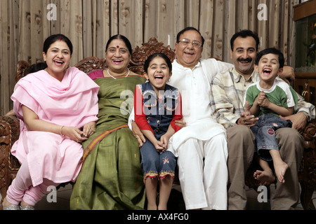 Portrait einer gemeinsamen Familie im Wohnzimmer sitzen und lachen Stockfoto