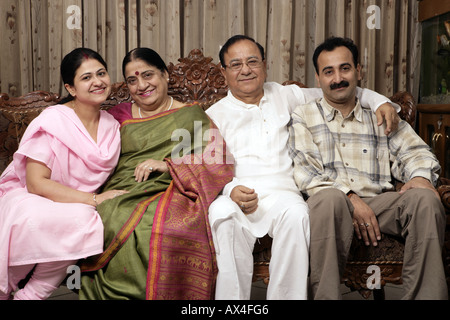 Portrait einer gemeinsamen Familie im Wohnzimmer sitzen und Lächeln Stockfoto