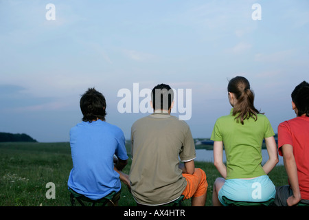 Vier junge Leute sitzen in einer Linie Stockfoto