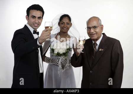 Porträt von einem Bräutigam und eine Braut mit ihrem Vater Wein zu trinken und lächelnd Stockfoto