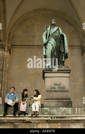 Drei asiatische Leute sitzen auf den oberen Stufen eines Denkmals Stockfoto
