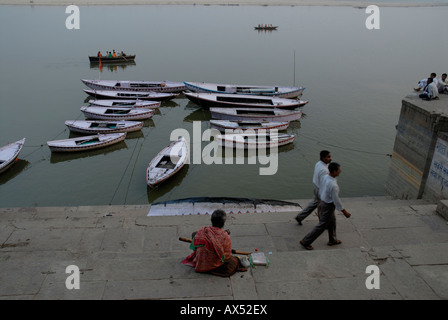 Boote vertäut am Fluss Ganges als ein Sadhu, den Sonnenaufgang auf den Ghats, Varanasi, Indien wartet Stockfoto