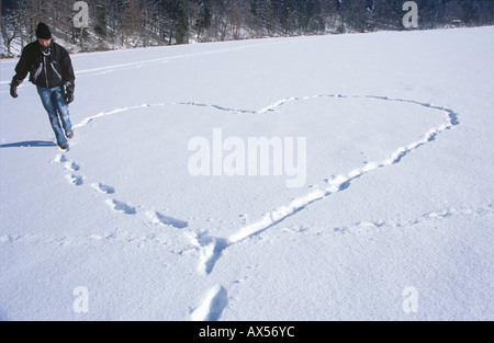 Mann zu Fuß in Schnee, indem Fußabdruck Herzform Stockfoto
