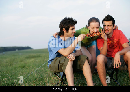 Vier junge Leute machen ein Barbecue vor einem Zelt Stockfoto