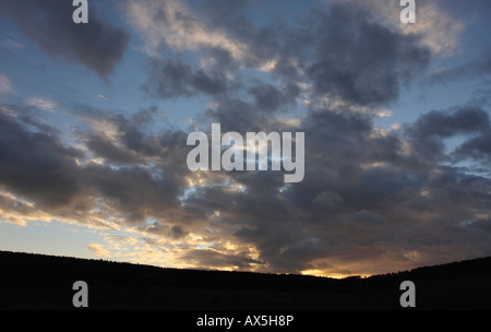 Gewitterwolken über eine dunkle Landschaft Sonnenstrahlen vor Sonnenuntergang Stockfoto