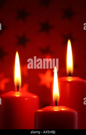 Brennende Kerze vor Rot Weihnachten Geschenkpapier mit Sternen Stockfoto