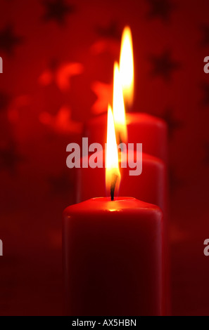 Brennende Kerze vor Rot Weihnachten Geschenkpapier mit Sternen Stockfoto