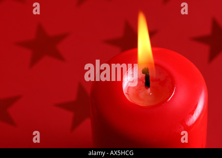 Brennende Kerze vor Rot Weihnachten Geschenkpapier mit Sternen Stockfoto
