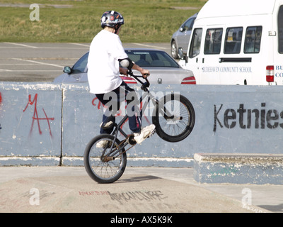 Kleiner Junge macht einen Wheelie auf einem BMX Skate Park Stockfoto