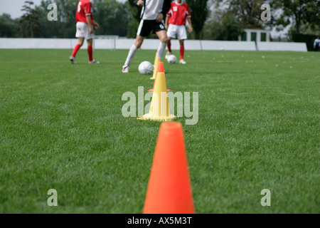 Fußball-Spieler laufen Slalom mit einem Fußball rund um Marken Stockfoto