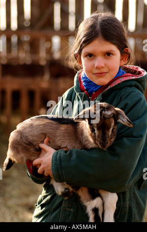 Mädchen hält eine Neugeborene Ziege (Capra) in ihre Arme, Othensdorf, Mecklenburg-Western Pomerania, Deutschland, Europa Stockfoto